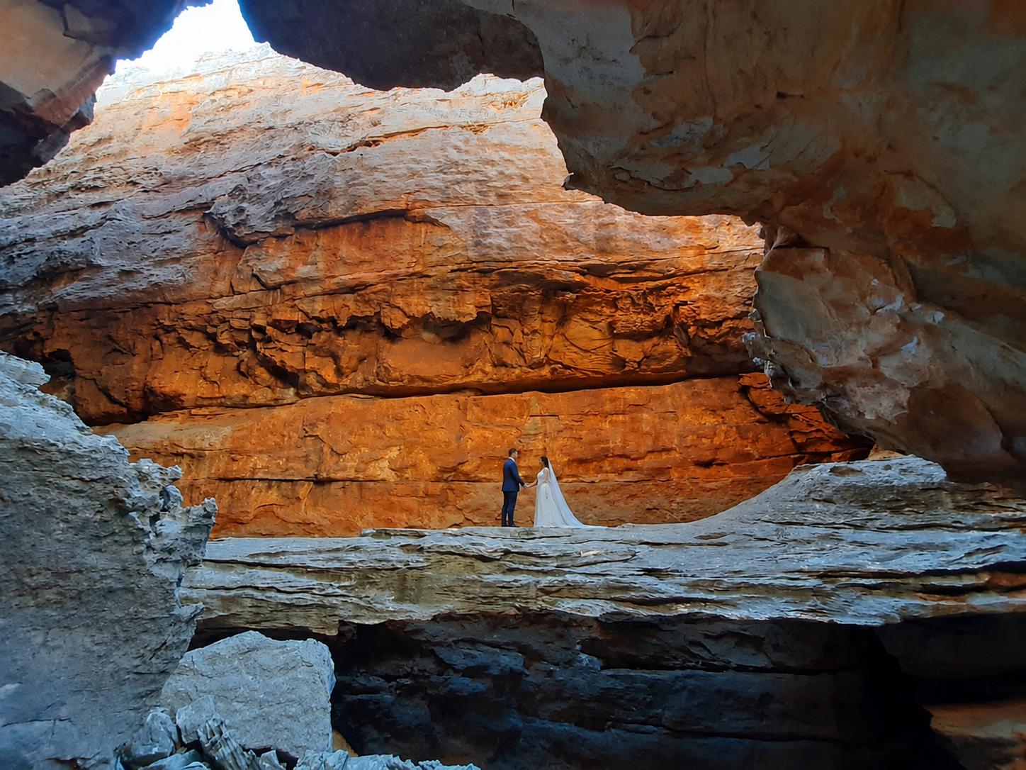 Couple holding hands inside a sandstone cave